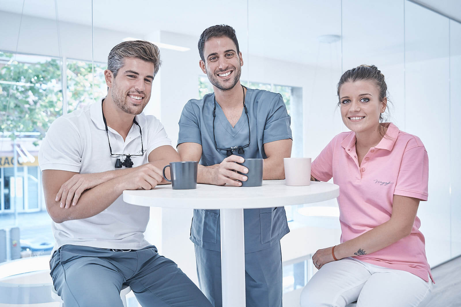 Firas, Basel y una compañera del equipo de la Clínica Nayef, sonriendo alrededor de una mesa